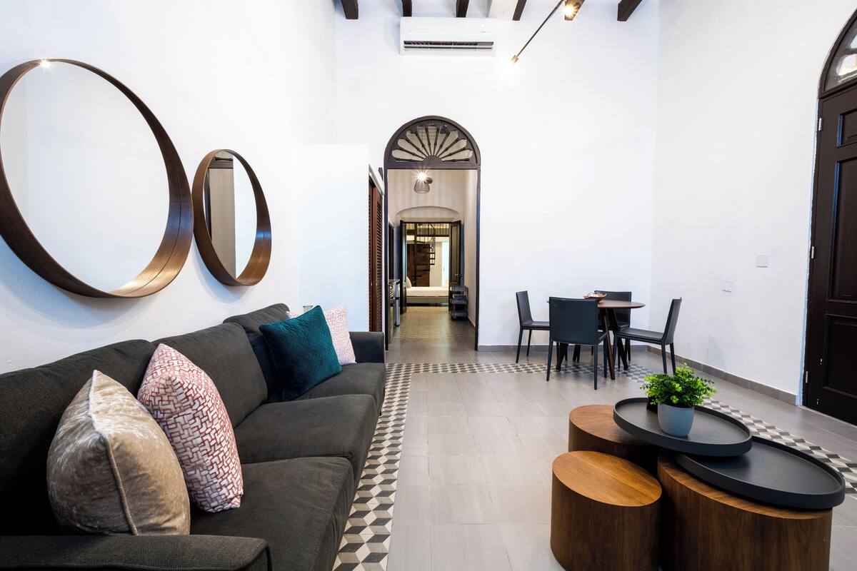 A modern interior with a sofa, a coffee table, and a dining area with chairs and a table.