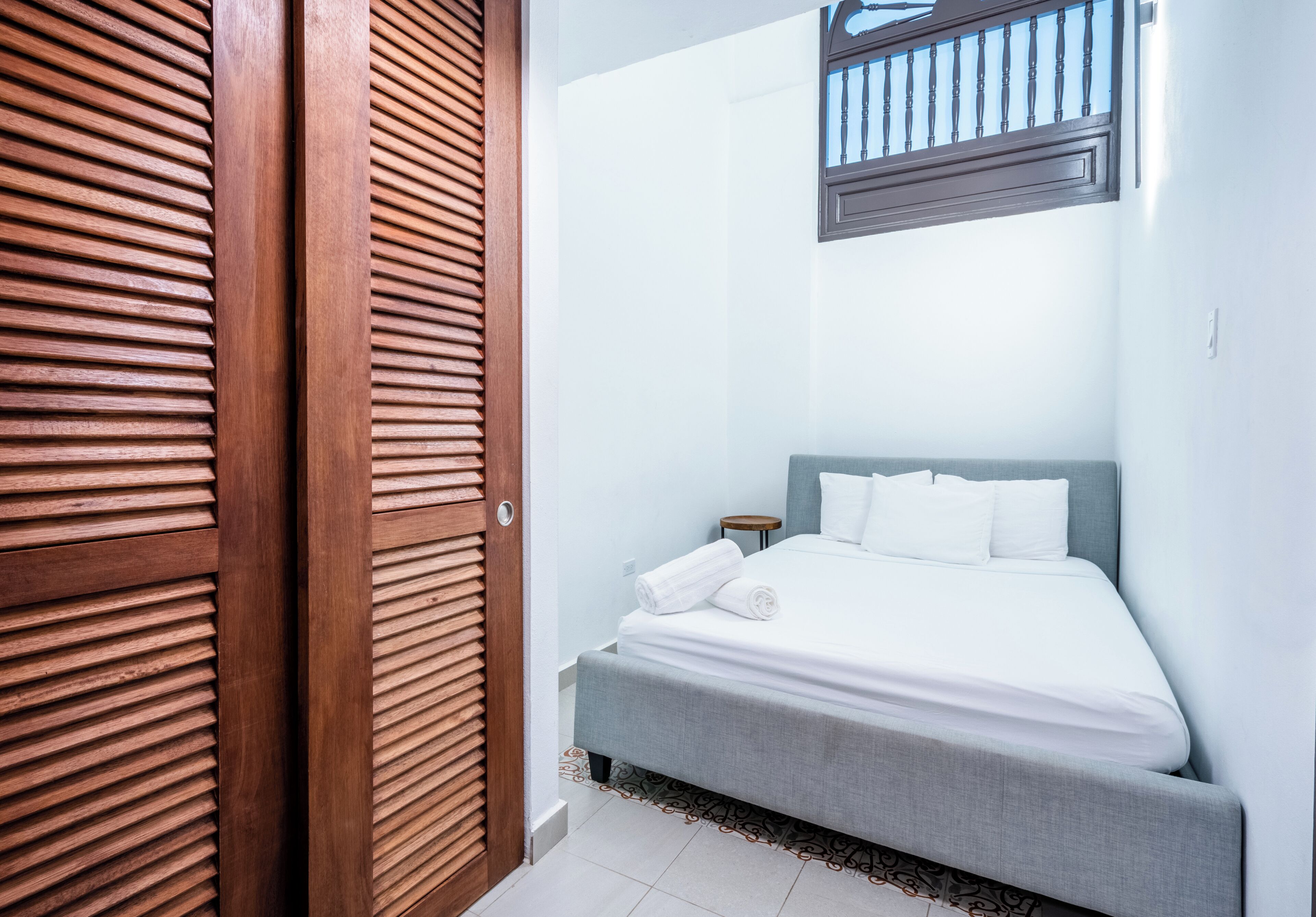 A bedroom with a bed, a nightstand, and a window with a view.