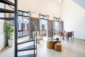 Une pièce spacieuse avec un escalier, un coin repas et de grandes fenêtres.