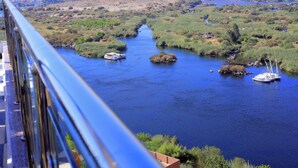 A river with boats, surrounded by greenery and hills.