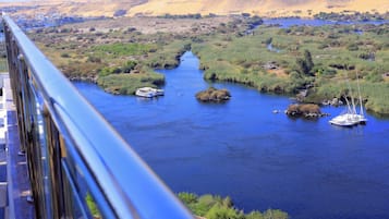 A river with boats, surrounded by greenery and hills.