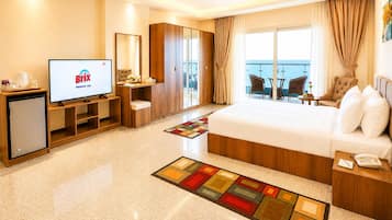 A hotel room with a bed, a TV, a desk, a chair, a small table, and a balcony with a view.
