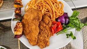 A plate of food with spaghetti, breaded chicken, and vegetables. - Blue Lotus Nile Suites (Aswan)