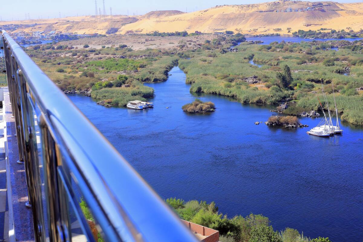A river with boats, surrounded by greenery and hills.