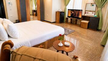 A hotel room with a bed, a TV, a desk, a mirror, and a bathroom visible through a door.