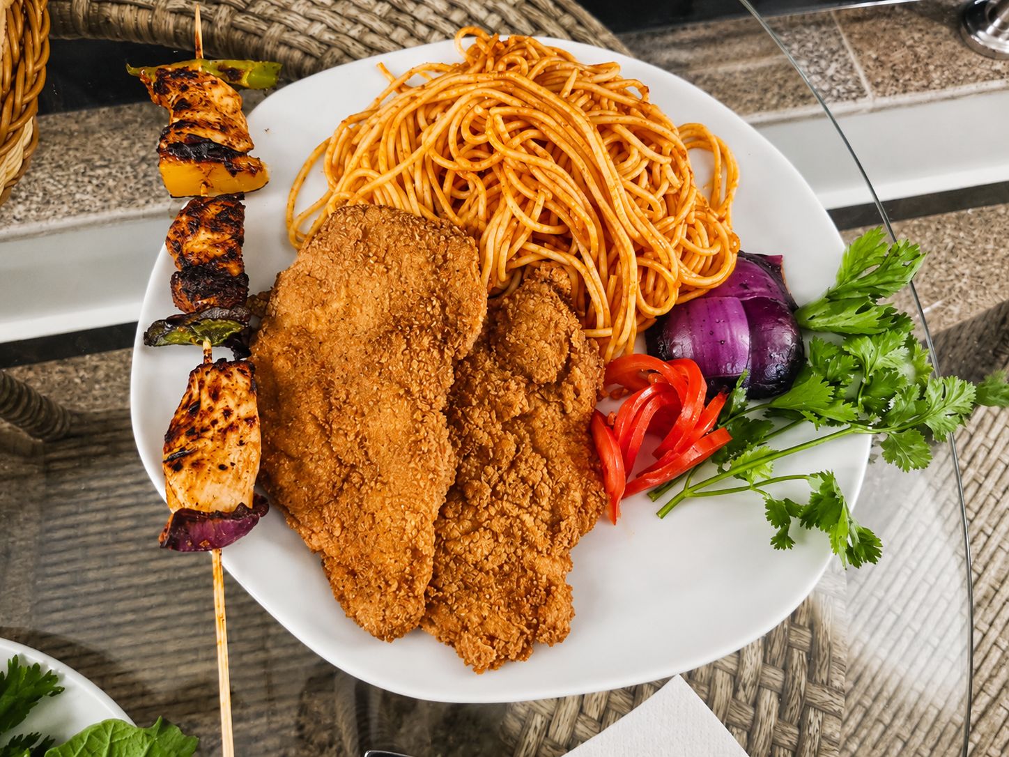 Ein Teller mit Spaghetti, paniertem Hähnchen und Gemüse.