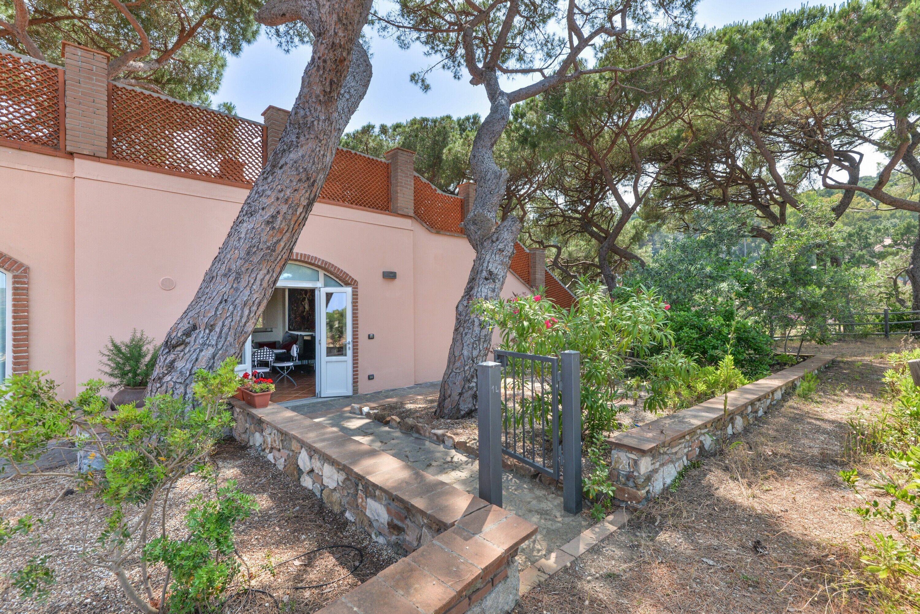 Une maison avec un chemin de pierres menant à une porte, entourée d’arbres et d’une clôture.