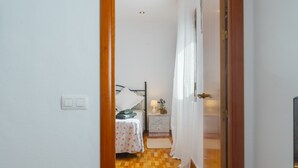 A bedroom with a bed, bedside table, lamp, and curtains. - Apartment 'Lolita' with Shared Garden, Wi-Fi and Air Conditioning (Carmona)