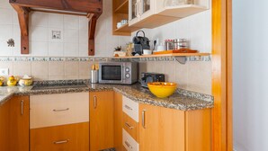 A kitchen with wooden cabinets, a granite countertop, a microwave, a toaster, and a yellow bowl. - Apartment 'Lolita' with Shared Garden, Wi-Fi and Air Conditioning (Carmona)