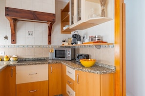 Una cucina con mobili in legno, un piano di lavoro in granito, un forno a microonde, un tostapane e una ciotola gialla.