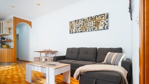 A living room with a sofa, coffee table, and a kitchen area with cabinets and a sink. - Apartment 'Lolita' with Shared Garden, Wi-Fi and Air Conditioning (Carmona)