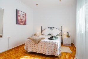 Une chambre à coucher avec un lit, des tables de chevet, un tableau accroché au mur et une fenêtre avec des rideaux.