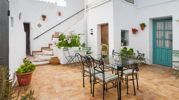 A courtyard with a table and chairs, potted plants, and a staircase. - Apartment 'Lolita' with Shared Garden, Wi-Fi and Air Conditioning (Carmona)