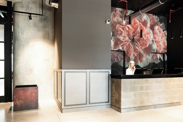 A reception area with a large floral mural, a reception desk, and a metal column. - Kira Suites Hotel Milano (Milan)