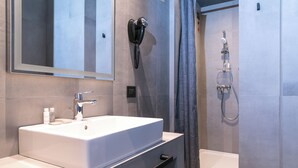 A modern bathroom with a large sink, a hairdryer, a shower, and a mirror. - Kira Suites Hotel Milano (Milan)