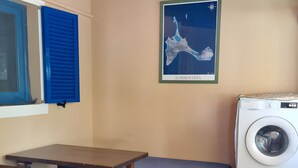Ein Zimmer mit Holztisch, Stühlen, einer Bank, einer Waschmaschine und einer Karte an der Wand.