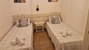 Ein Zimmer mit zwei Betten, einem Schreibtisch und zwei Bildern an der Wand.