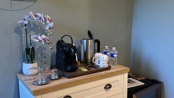 A kitchenette with a coffee maker, kettle, and tea set on the counter.