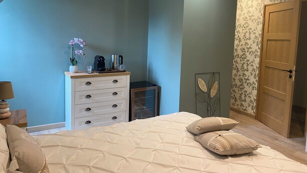 A bedroom with a bed, a dresser, a coffee maker, and a door. - Domaine de Lithos (Fossemagne)