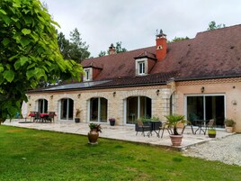 A stone building with a tiled roof, outdoor seating, and a grassy courtyard.