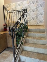 A staircase with a metal railing and a patterned wallpaper background.