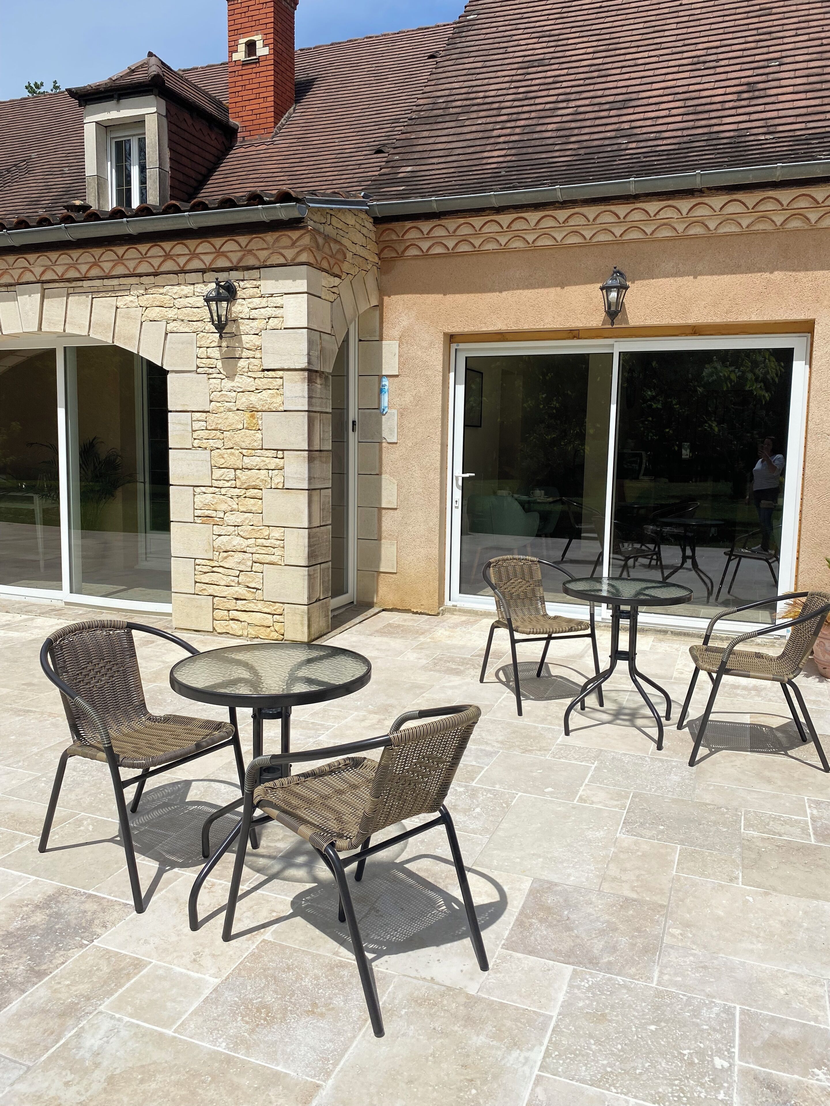 An outdoor patio area with stone flooring, wicker chairs, and a glass door leading to an interior space.