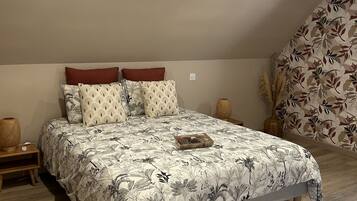 A bedroom with a large bed, a nightstand, a decorative vase, and a patterned wall.