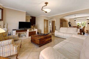 A living room with a sofa, a television, a wooden coffee table, and a dining area with a table and chairs. - Villa Ramos – Retreat in Lagos (Lagos)