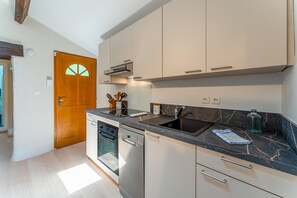 Eine moderne Küche mit weißen Schränken, einer schwarzen Arbeitsplatte und einem eingebauten Geschirrspüler.