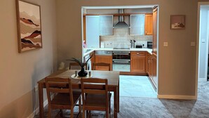 Eine moderne Küche mit Holzausbau, einem eingebauten Backofen und einem Essbereich mit Tisch und Stühlen.