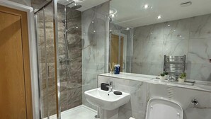 Ein modernes Badezimmer mit einer Duschkabine, einem Standwaschbecken und einer Toilette.
