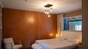 Une chambre à coucher avec un grand lit, une armoire en bois, une chaise et une table de chevet avec une lampe.