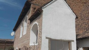 A traditional building with a white facade, a brick roof, and a small staircase leading to a door.