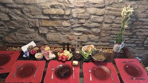 A stone wall background with a table set for a meal, including plates, cutlery, and various food items.