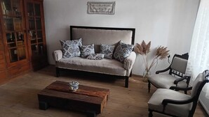 A living room with a sofa, a coffee table, and a chair. There is a wooden cabinet and a vase with pampas grass.