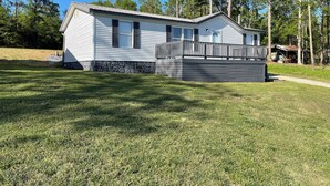 A single-story house with a stone foundation, a front porch with a railing, and a garage attached to the right. - 3-bedroom home on beautiful Lake Greenwood, close to Old Eight Golf Course. (Waterloo)