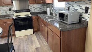 A kitchen with wooden cabinets, a stainless steel stove, a microwave, and a tiled backsplash. - 3-bedroom home on beautiful Lake Greenwood, close to Old Eight Golf Course. (Waterloo)