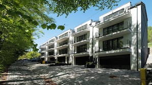 Een modern meerhooggezinsgebouw met balkons, een verharde oprit en een heldere lucht.