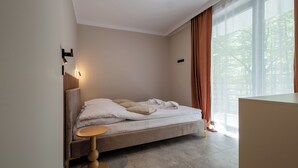 Een moderne slaapkamer met een bed, een nachtkastje en een raam met gordijnen.