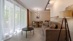 Een moderne woonkamer met een bank, een eettafel met stoelen, een bijzettafeltje en een vloerlamp.