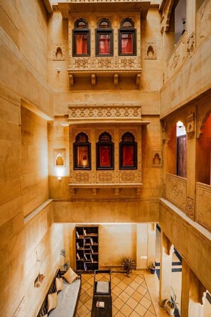 Um interior em vários níveis com detalhes arquitetônicos elaborados, uma área de estar central e uma parede decorativa com obras de arte emolduradas.