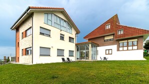 A two-story house with a sloped roof, a glass conservatory, and a grassy yard. - Apartment 'Gloria-Patchwork' with Sea View, Shared Garden and Wi-Fi (Ubiarco)