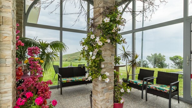 A covered outdoor seating area with stone pillars, potted plants, and a view of the landscape. - Apartment 'Gloria-Patchwork' with Sea View, Shared Garden and Wi-Fi (Ubiarco)