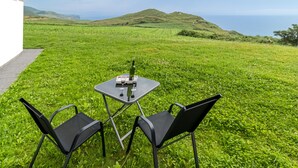A grassy outdoor area with a table and two chairs, overlooking a hilly landscape and the sea. - Apartment 'Gloria-Patchwork' with Sea View, Shared Garden and Wi-Fi (Ubiarco)
