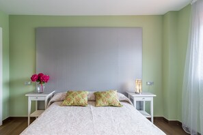 Une chambre à coucher avec un grand lit, deux tables de chevet, un vase avec des fleurs et une lampe sur l’une des tables de chevet.