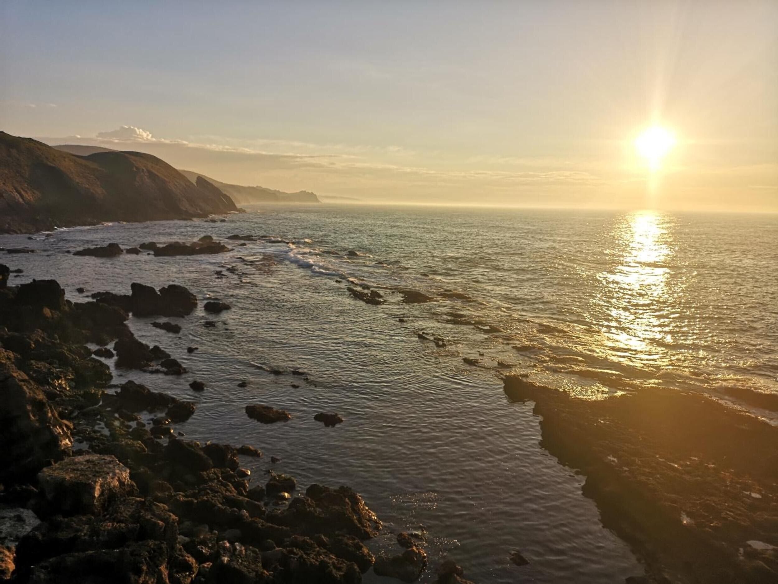 A coastal landscape with rocky terrain and the ocean.