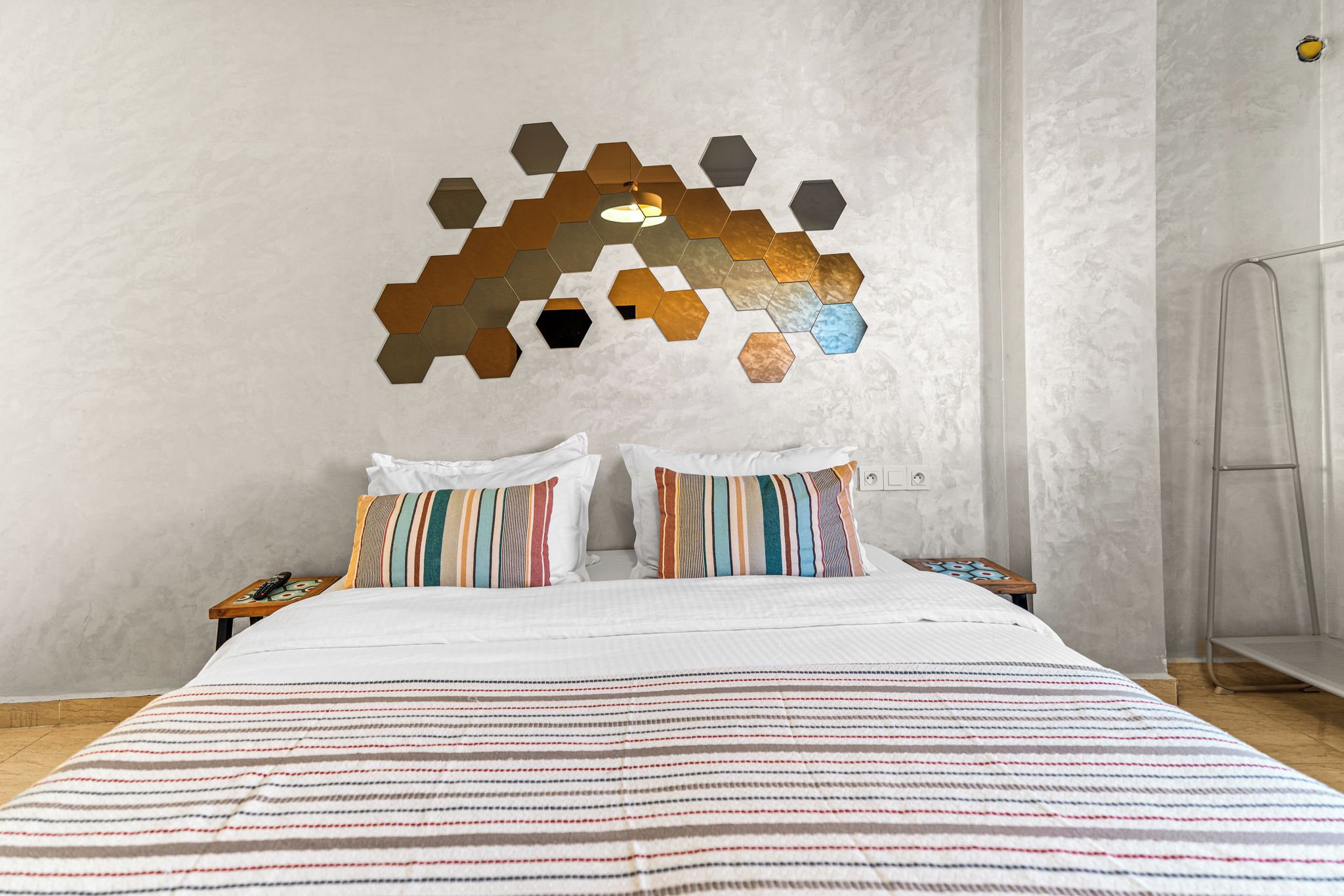 A bedroom with a large bed, two pillows, a bedside table, and a wall decoration.