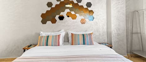 A bedroom with a large bed, two pillows, a bedside table, and a wall decoration.