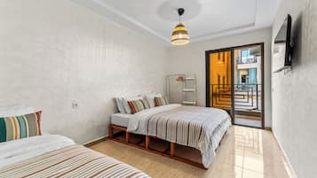 A hotel room with a bed, a bedside table, a wardrobe, a hanging light fixture, and a view of the outside.