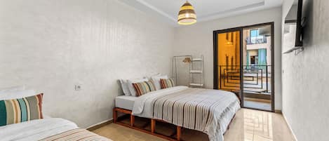 Habitación de hotel con cama, mesita de noche, armario, lámpara colgante y vista al exterior.